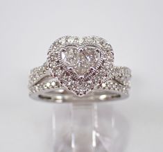 a heart shaped diamond ring with two rows of diamonds on the band, set in 18k white gold