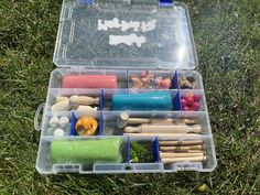 a plastic container filled with lots of different types of items in it on the grass