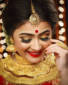 a woman wearing gold and red makeup is posing for the camera with lights in the background