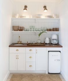 a kitchen with white cabinets and wooden counter tops