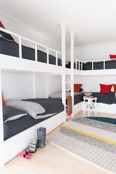 the bunk beds are all white and have red pillows on them