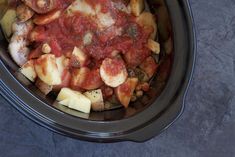 a slow cooker filled with meat and cheese covered in marinara sauce on the side