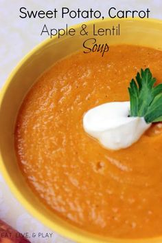 a yellow bowl filled with carrot soup and topped with a small green leafy garnish