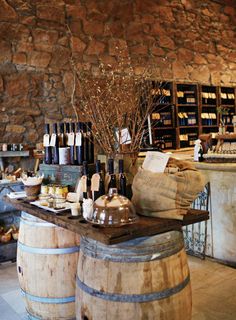 wine bottles are sitting on top of wooden barrels in front of a stone wall and counter