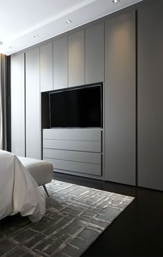 a bedroom with white furniture and a flat screen tv mounted on the wall above it