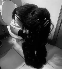 a woman with long hair sitting on top of a toilet