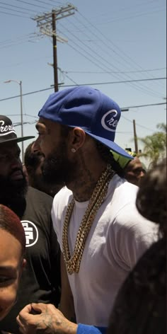 two men standing next to each other in front of power lines, one wearing a blue hat and the other wearing a white t - shirt