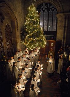 a group of people standing in front of a christmas tree with lit candles on it