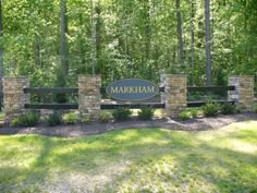 the entrance sign to markham park is surrounded by stone and brick pillars, with trees in the background