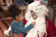 a little boy sitting next to santa clause