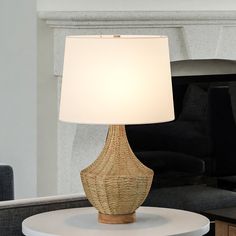 a table lamp sitting on top of a white table next to a couch in a living room