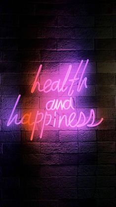 a neon sign that says health and happiness on a brick wall in front of it