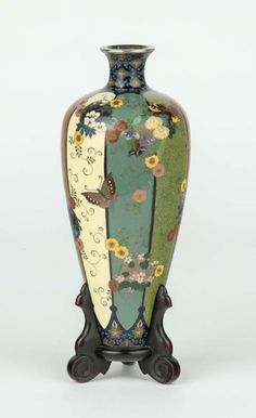 a vase with flowers and butterflies painted on the front is standing upright against a white background