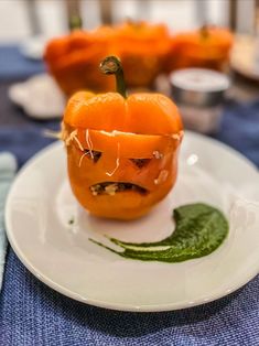 a white plate topped with an orange and green pepper covered in melted cheese on top of it