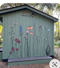 a green shed with flowers painted on the side