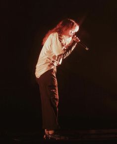 a man with long hair standing on top of a stage holding a microphone in his hand