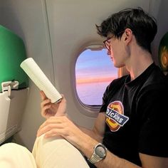 a man sitting on an airplane reading a book