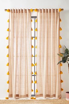 a window with yellow pom - poms hanging from it's curtain rod