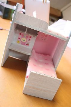 an open doll house sitting on top of a wooden table