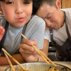 a man and woman eating food with chopsticks