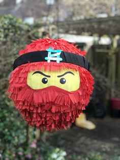 a close up of a paper mache head hanging from a tree in a yard