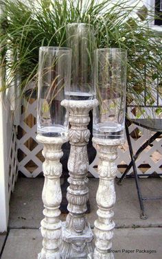 two clear glass candlesticks sitting next to a potted plant in front of a house