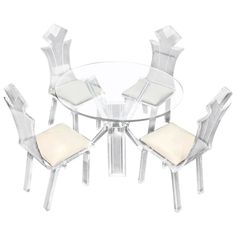 a glass table with four chairs and a white cushioned chair in front of it