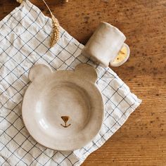 a white bear dish sitting on top of a table next to a cup and saucer