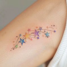 a woman's arm with colorful stars on it and a small star tattoo in the middle