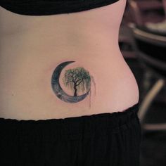 a woman with a tree and moon tattoo on her stomach