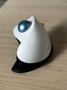 a white and blue object sitting on top of a wooden table next to a mouse