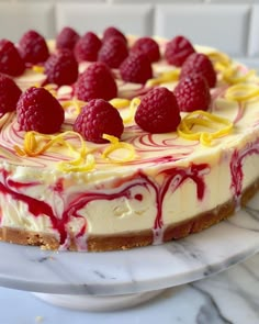 a cheesecake with raspberries on top is sitting on a marble platter