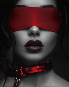 a woman with red tape on her face and blindfold over her eyes, looking down at the camera