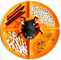 an orange plate with black and white decorations on it that has a spider in the center