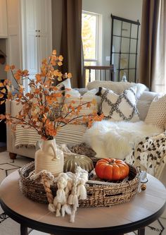 a living room filled with white furniture and lots of fall decorations on the coffee table