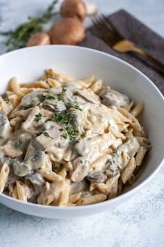 a white bowl filled with pasta covered in mushroom sauce and garnished with parsley