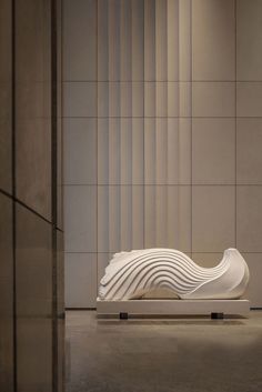 a white sculpture sitting on top of a floor in front of a wall with vertical blinds