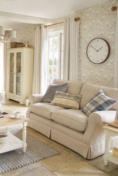 a living room filled with furniture and a clock mounted on the wall above it's windows