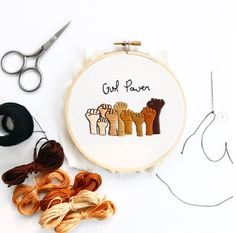 a cross stitch project with scissors and thread on a white table next to some yarn