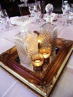 there are many glasses and candles on the tray at the dinner table with white linens