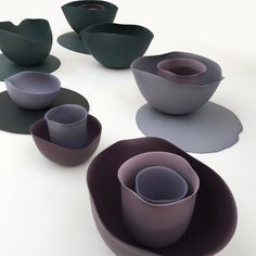 there are many bowls and cups on the table together, all in shades of purple