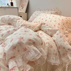 an unmade bed with pink flowers and ruffled bedspread on top of it