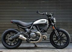 a black and white motorcycle parked in front of a garage door