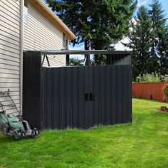 a lawn mower sitting next to a shed on the side of a house with grass