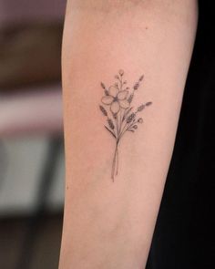 a small flower tattoo on the left arm