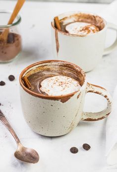 two mugs filled with hot chocolate and topped with cinnamon