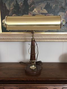 an old fashioned lamp is on top of a wooden table in front of a painting