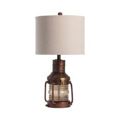 an old fashioned lamp with a white shade on the top and brown metal cage around it