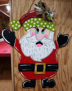 a wooden sign with a santa clause on it's face and green polka dot hat