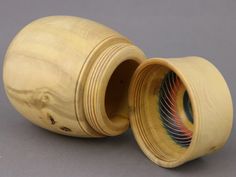 two wooden vases sitting side by side on a gray surface, one is empty and the other has an open lid